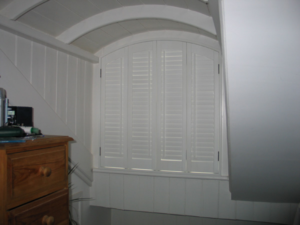 Shaped plantation shutters, silk white in wood with 47mm louvres and offset tilt rods